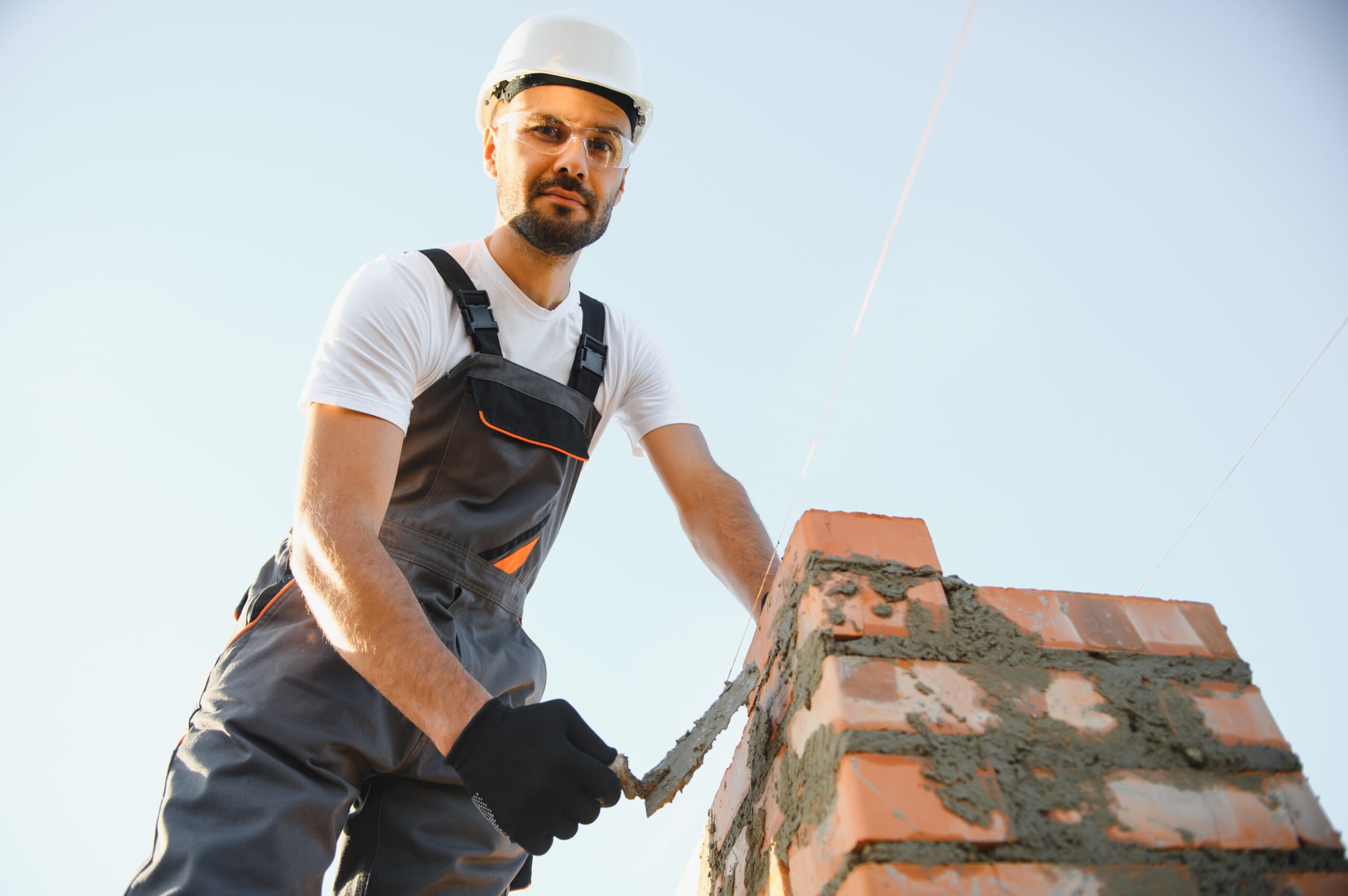 Installing brick wall. Construction worker in uniform and safety equipment have job on building čistič komína, čistenie komína