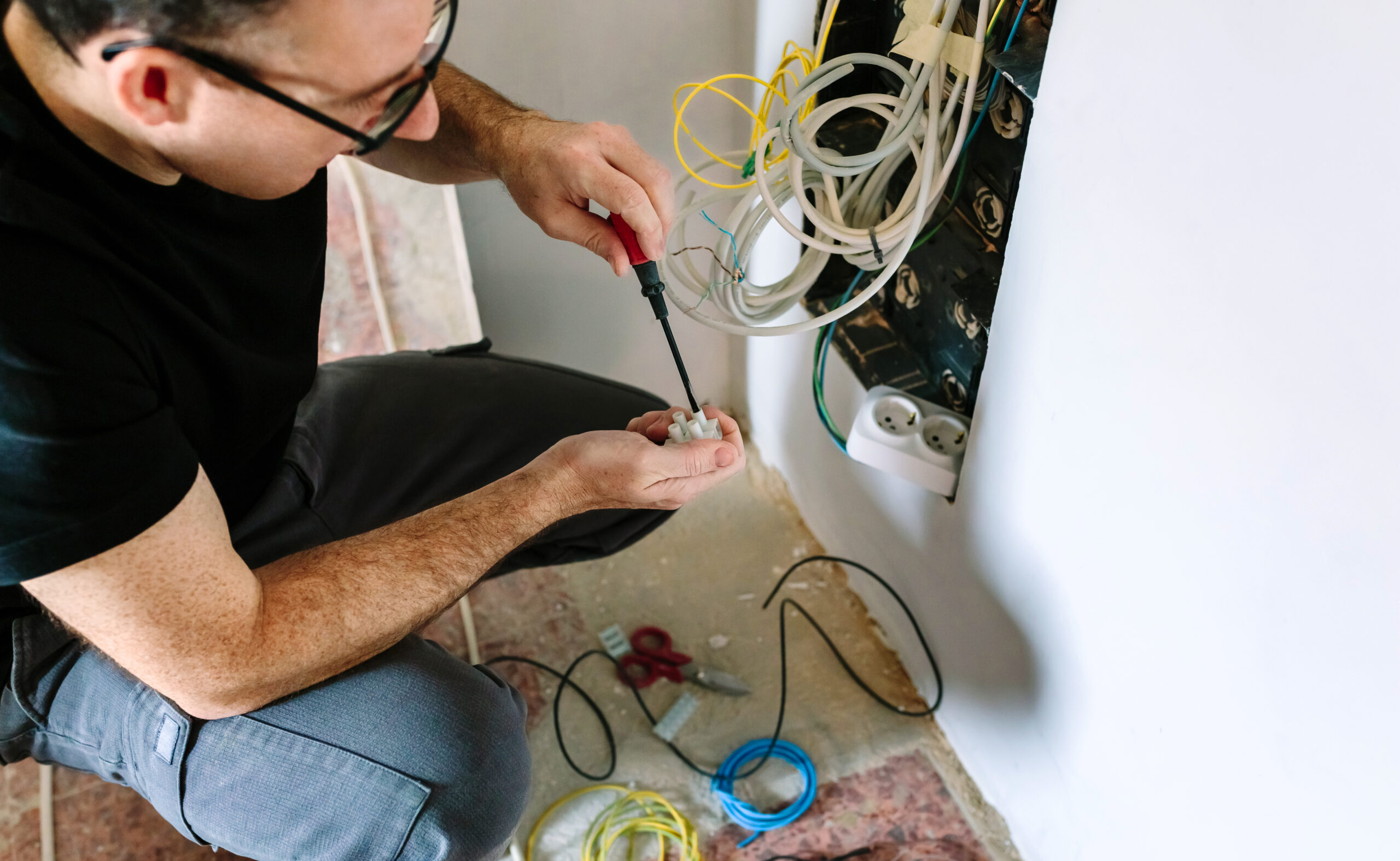 Technician with screwdriver and terminal strip installing telecommunication box revízia elektriny v byte, revízia elektriny v byte cena