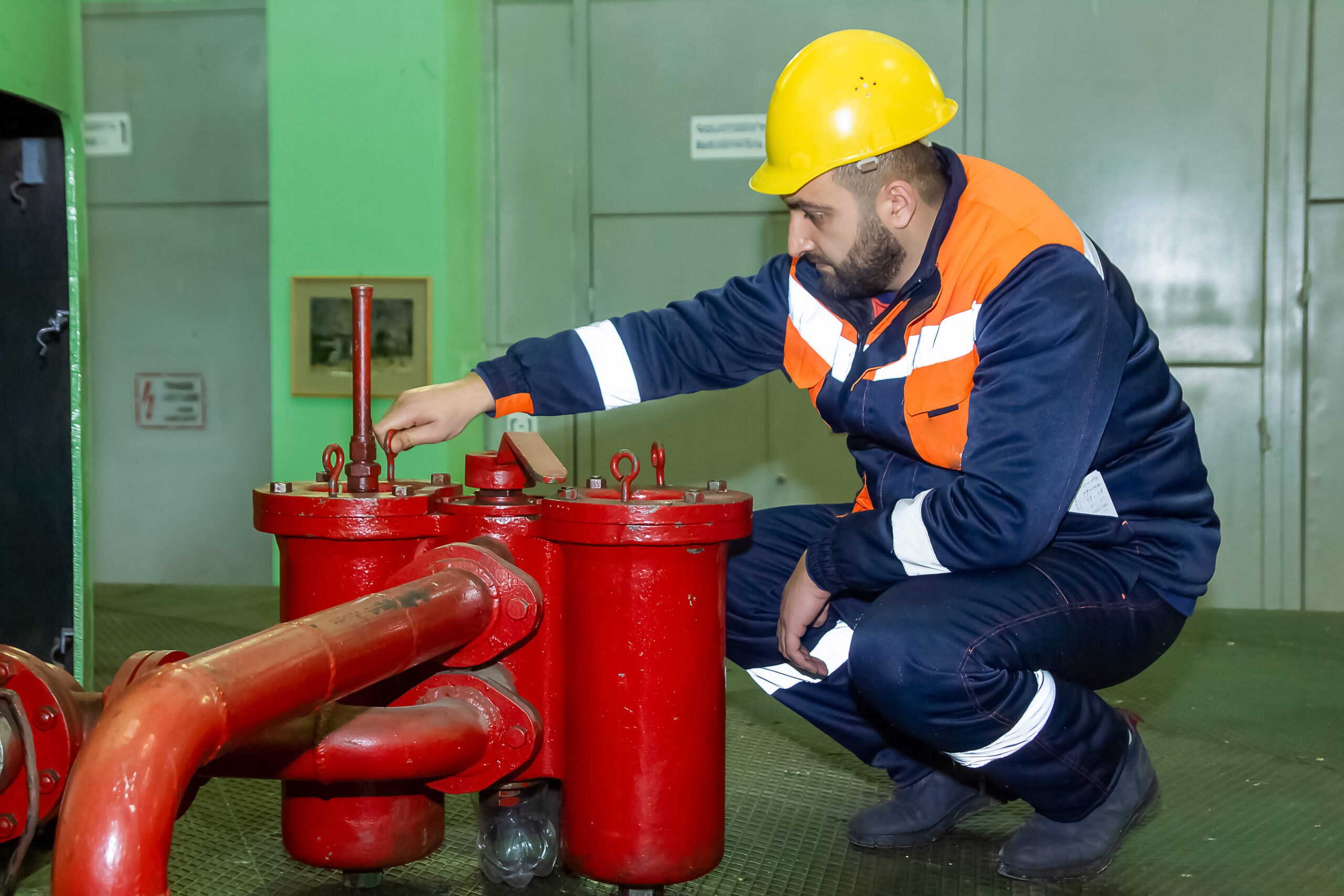 View of a mechanical engineer with a yellow helmet on his head fixing the equipment in a factory revízie plynových zariadení cenník, revízia gamatiek cena